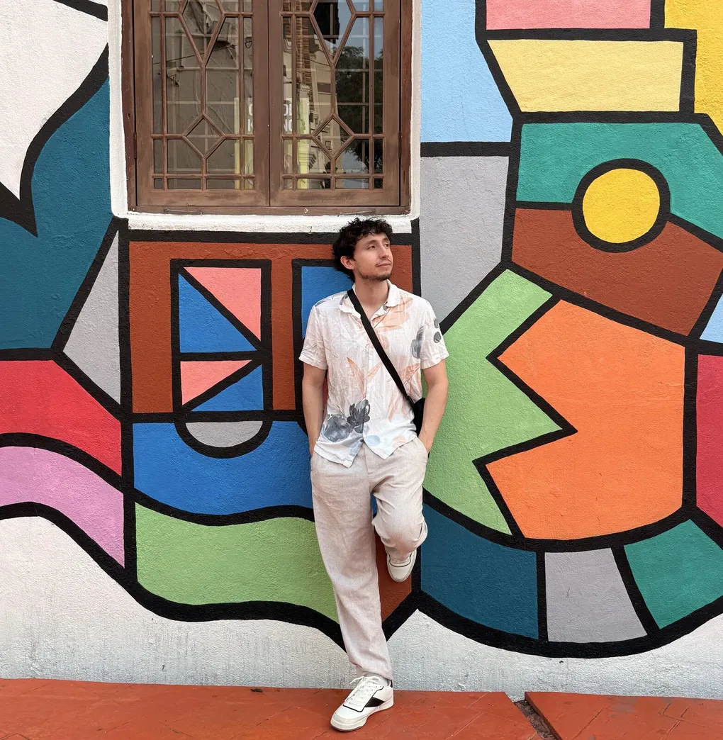 Joey Alvarado standing in front of a colorful mural
